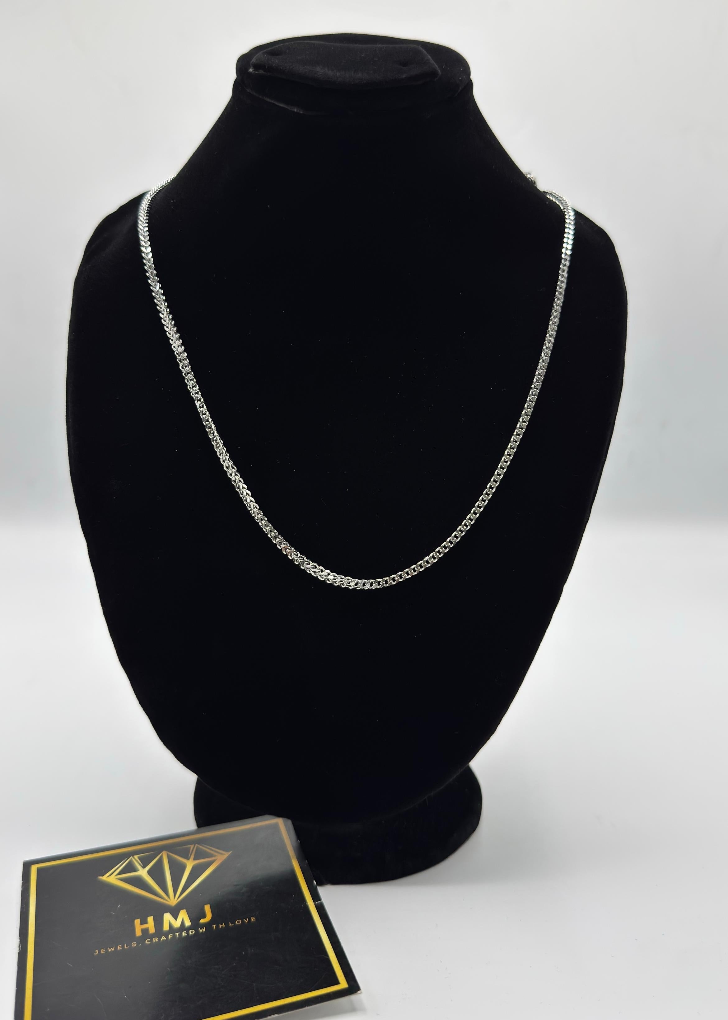 Silver necklace on a black mannequin bust with a branded card below on a white background
