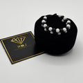 Black beaded bracelet on a black cushion with an HMJ card on a white background