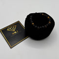 Black beaded bracelet in a black pouch with an HMJ card on a white background