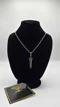 Silver dagger necklace on a black mannequin bust with a branded card below.