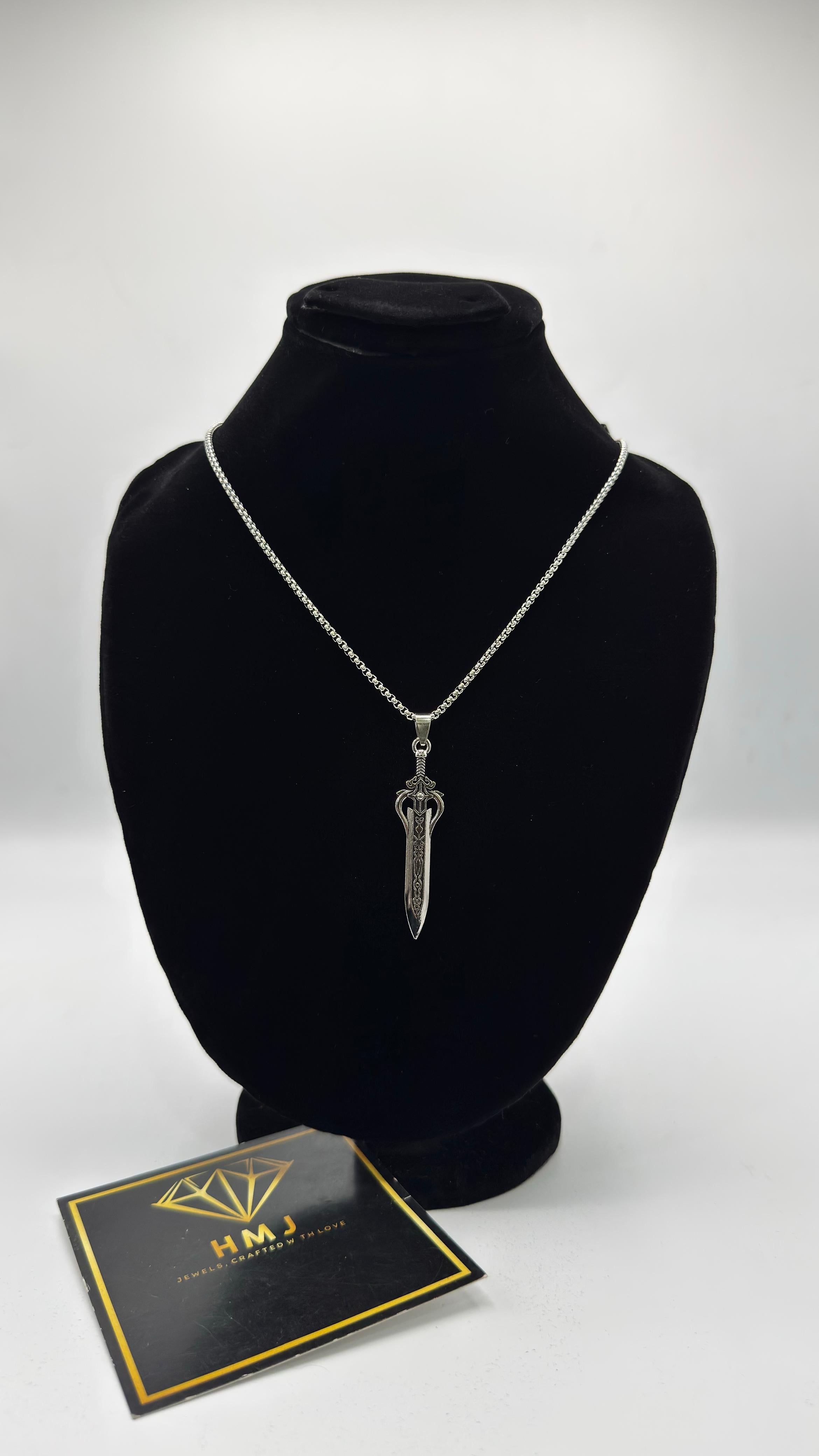 Silver dagger necklace on a black mannequin bust with a branded card below.