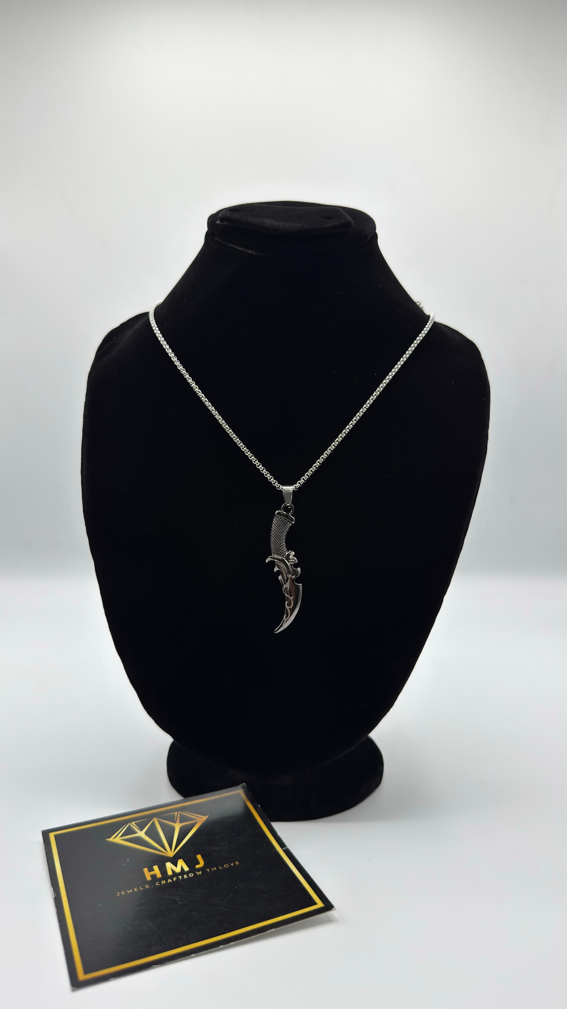 Silver necklace on a black mannequin bust with a branded card below on a white background